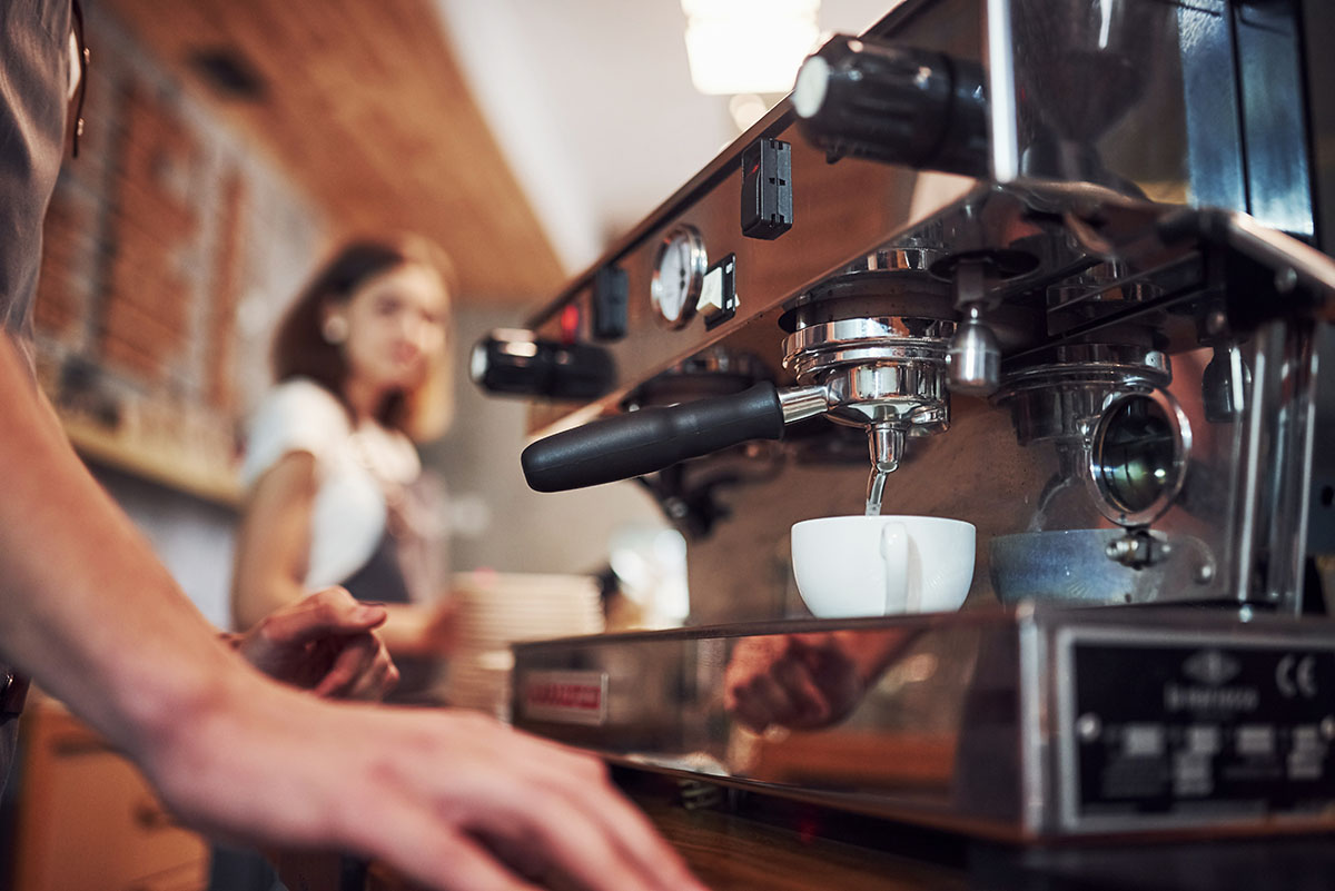 Process of making fresh drink. With machine. Two young cafe workers indoors. Conception of business and service